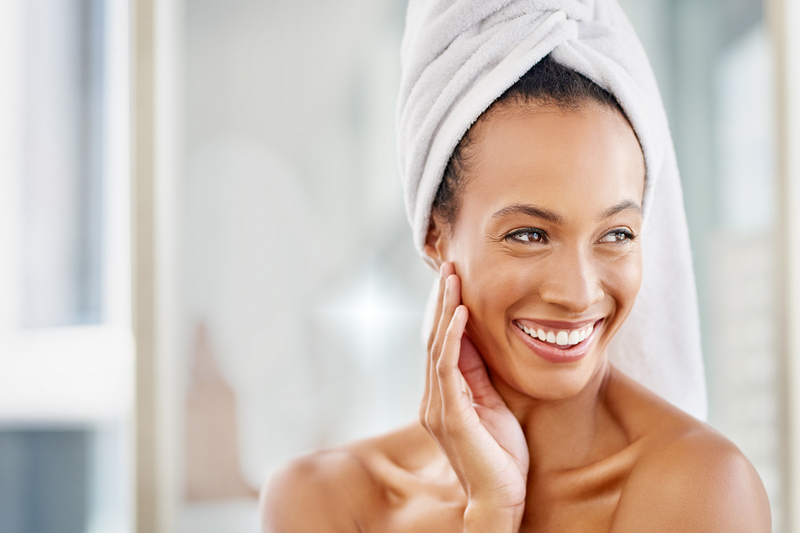 Model woman with her hair wrapped in a towel smiling after using Nu Skin Rejuvenating Cream.
